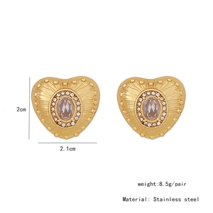 Detail view of heart-shaped gold steel studs with oval zircon and textured engraving