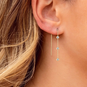 Close-up of golden S925 silver long chain earrings with three sparkling zircons on model