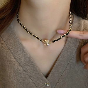 Collier en cuir vintage avec finition dorée et pendentif en strass porté par un modèle