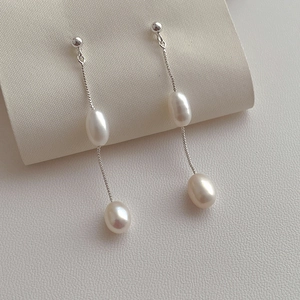 Close-up of long tassel earrings with teardrop freshwater pearls on silver chains