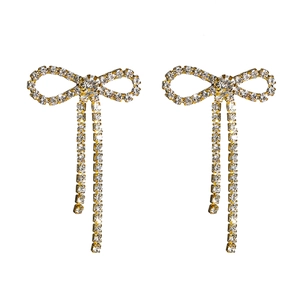 Close-up of golden bow earrings with sparkling rhinestone tassels and elegant crystal fringe
