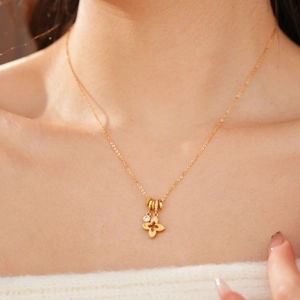 Detail shot of a golden four-leaf flower pendant necklace with shimmering zircon crystals