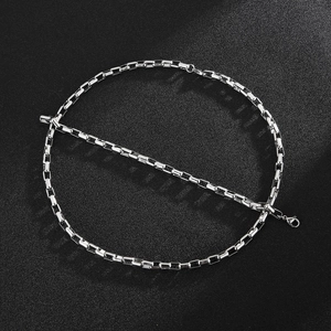 Macro view of silver square link chain necklace with lobster clasp on black background