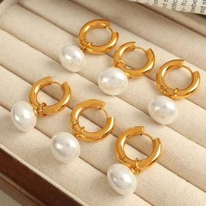 Elegant gold hoop earrings with white freshwater pearls displayed on a velvet jewelry box