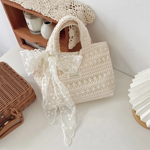 Detailed close-up of crochet lace tote bag with floral patterns and a large bow