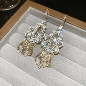 Macro shot of sparkling water drop tassel earrings with opal beads and crystals