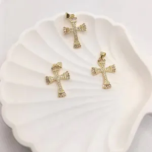Detailed view of three 18K gold cross pendants with cubic zirconia in a white shell tray