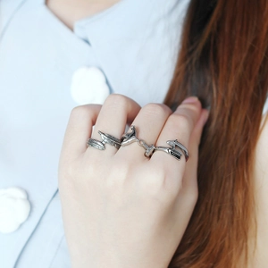 Detail of silver feather and fish open rings worn on fingers with a vintage aesthetic