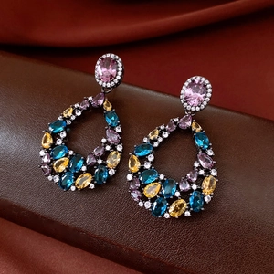Detail of vintage hollow teardrop earrings with multi-color zircon stones and gold finish