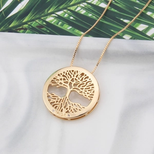 Macro shot of 18k gold plated Tree of Life pendant with VIDA engraving on marble tray