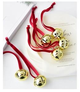 Detail of golden metal Christmas bells with red velvet ribbons on elegant white background