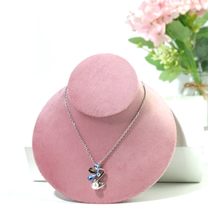 Detail of butterfly crystal pendant and pearl necklace on pink velvet bust stand