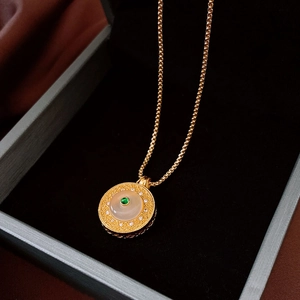 Detail of vintage gold necklace with white agate pendant and green gemstone in luxury box