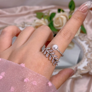 Detail of silver leaf ring with marquise zircon and pearl on elegant silk background