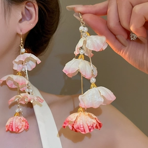 Détail de boucles d'oreilles fleurs en tissu rose avec perles sur mannequin
