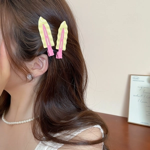 Detail shot of wavy pink and yellow matte spray paint hair clips on a female model
