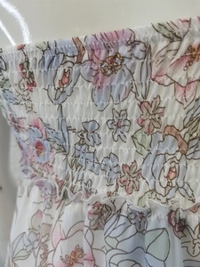 Detailed close-up of smocked floral fabric and ruffle texture in pastel pink and blue