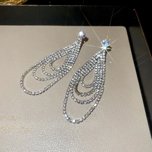 Détail macro de boucles d'oreilles argentées avec glands à trois couches et cristaux brillants
