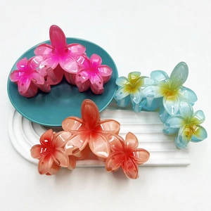 Three gradient colored 11.5cm plumeria hair claws on a decorative display plate