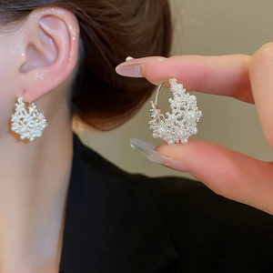 Detail of U-shaped silver hoop earrings with cluster of white pearls for a luxury look