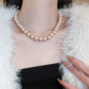 Dettaglio della collana di perle color champagne indossata da una modella su outfit elegante