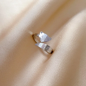 Macro detail of silver adjustable ring with Love engraving on champagne silk background
