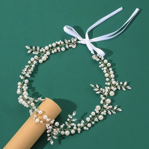 Détail macro d'un bandeau de mariée avec fils dorés, perles et cristaux sur rubans blancs