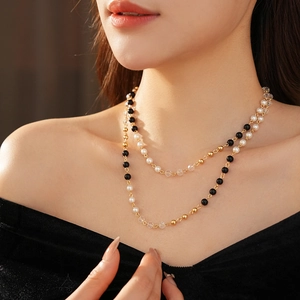 Gros plan détaillé d'un collier à deux rangs avec perles noires, blanches et dorées