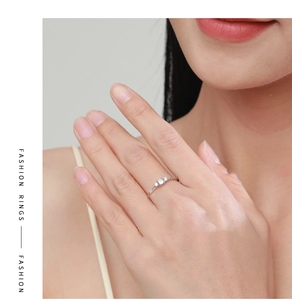 Detail of silver S925 ring with three sparkling crystals and twisted band on a finger