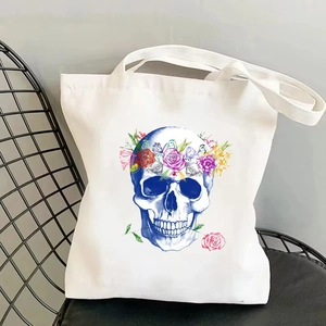 Close-up of vintage canvas tote bag with floral skull print on a black metal chair