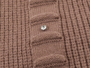 Macro shot of brown knit cardigan featuring a sparkling rhinestone round button detail
