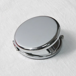 Macro shot of polished silver metal pocket mirror showing a smooth reflective surface