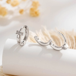 Elegante Creolen in Silber mit Zirkonia-Inlay auf warmem, strukturiertem Hintergrund