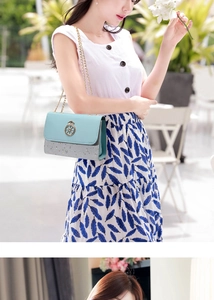 Close-up of light blue pebble leather crossbody bag with silver sequins and gold chain strap