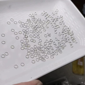Polished silver jump rings for DIY jewelry making displayed on a white tray