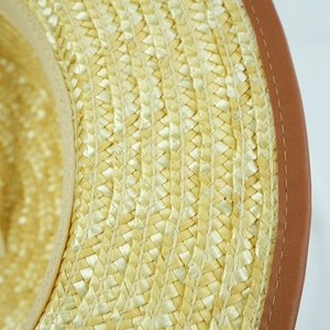 Macro detail of natural straw weave and premium brown leather trim on a vintage sun hat