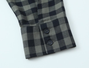 Detail of checkered shirt cuff with two navy buttons and sharp twill texture on grey fabric