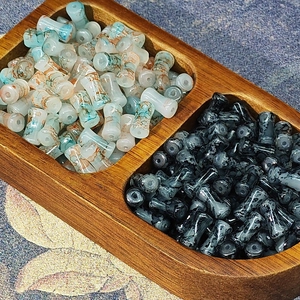 Ink-wash style bamboo glass beads in light blue and black shown in a wooden tray
