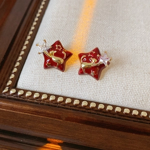 Detailed close-up of red enamel star stud earrings with gold silhouette and zircon inlay
