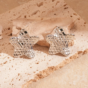 Vue macro de boucles d'oreilles étoile argentées avec texture en losanges sur pierre