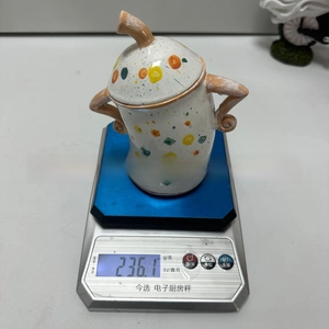 Detail view of colorful speckled ceramic jar with handles being weighed on a scale