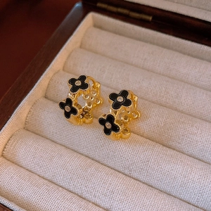 Detailed close-up of C-shaped gold floral earrings with black clover and central zircon