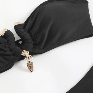 Détail de bikini noir avec anneau en métal doré et pendentif triangle gravé