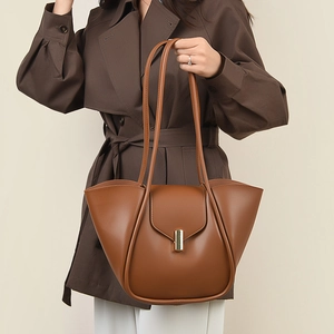 Détail du sac à main en cuir marron avec fermoir doré sur un trench-coat d'automne