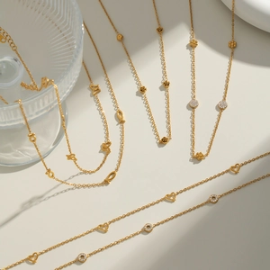 Detail of 18K gold titanium steel necklaces with rose, butterfly, and rhinestone charms