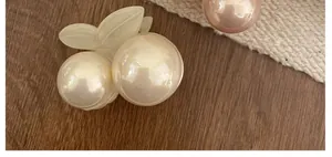Detailed close-up of a cherry-shaped hair clip featuring pearlescent white beads and leaves