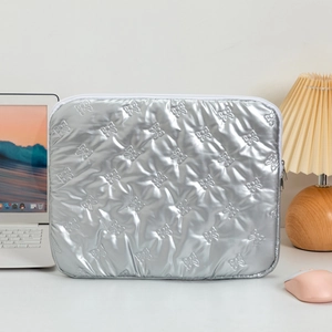 Detailed view of silver quilted laptop sleeve with embossed bow patterns and zipper