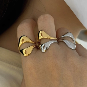 Detail view of irregular fluid rings in gold and silver finish worn on fingers
