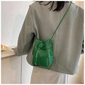 Detail of emerald green woven bucket bag with leather drawstring and shoulder strap