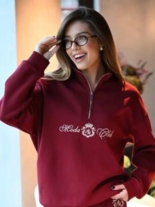 Detail of burgundy half-zip fleece sweatshirt featuring crown embroidery and ribbed collar